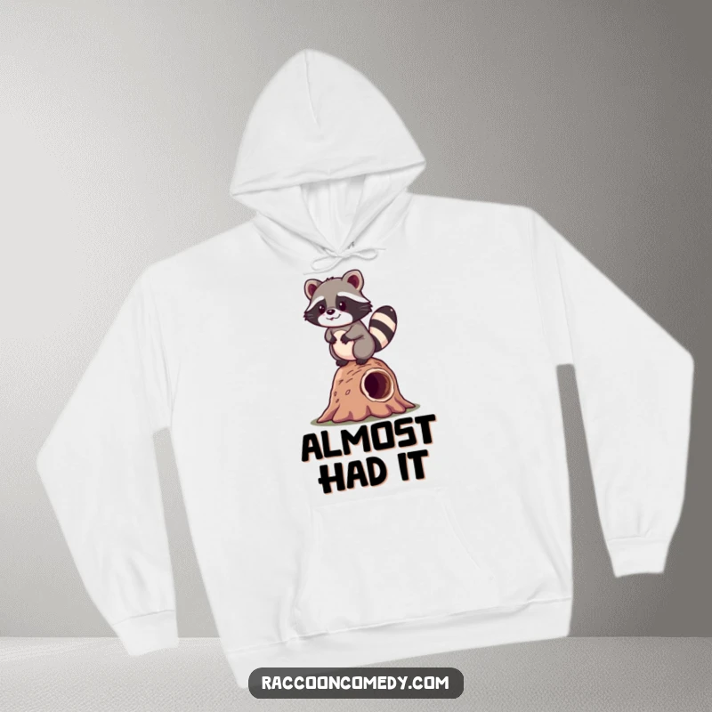 Funny kawaii raccoon wobbling happily on a log, featured on a warm and humorous hoodie for cozy wear.